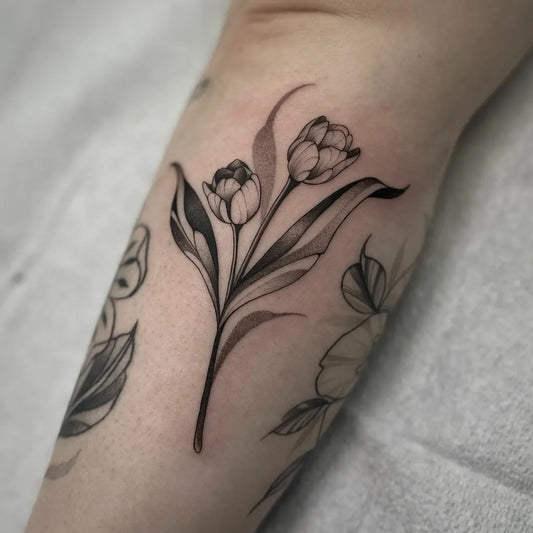 Small Blackwork Tulip and Leaves Tattoo on Women Forearm by @hailstorm.ink
