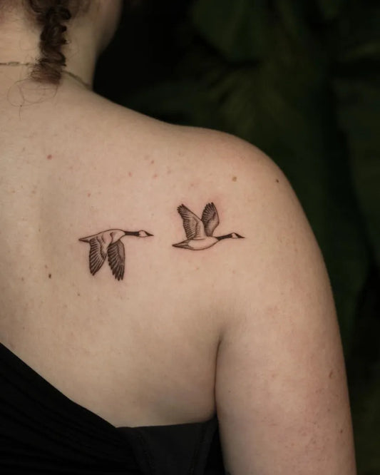 Small Blackwork Two Geese Bird Tattoo on Women Shoulder by @pauline.tattoo