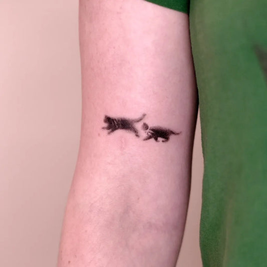 Small Blackwork Two Playing Cats Tattoo on Men Arm by @snappy.dots