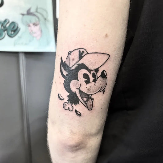 Small Blackwork Wolf Cartoon Tattoo on Women Arm by @anthologic.art