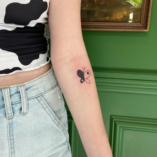Small Blackwork Yin Yang Butterfly Tattoo on Women Arm by @mclametattoos