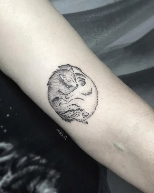 Small Blackwork Yin Yang Foxes Tattoo on Women Arm by @lunanuovastudio