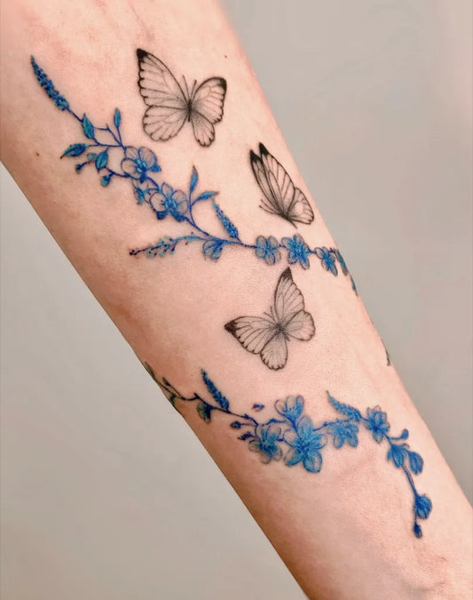 Small Blue Butterflies and Flowers Tattoo on Women Arm by @mariadelmar.tattoo