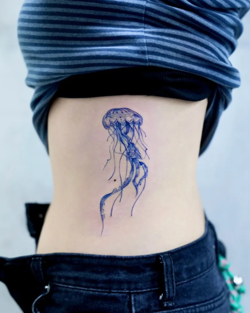 Small Blue Jellyfish Tattoo on Women Back by @tattooist_taker