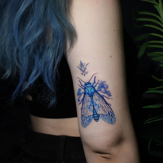 Small Blue Moth with Flowers Tattoo on Women Arm by @chinart.ink