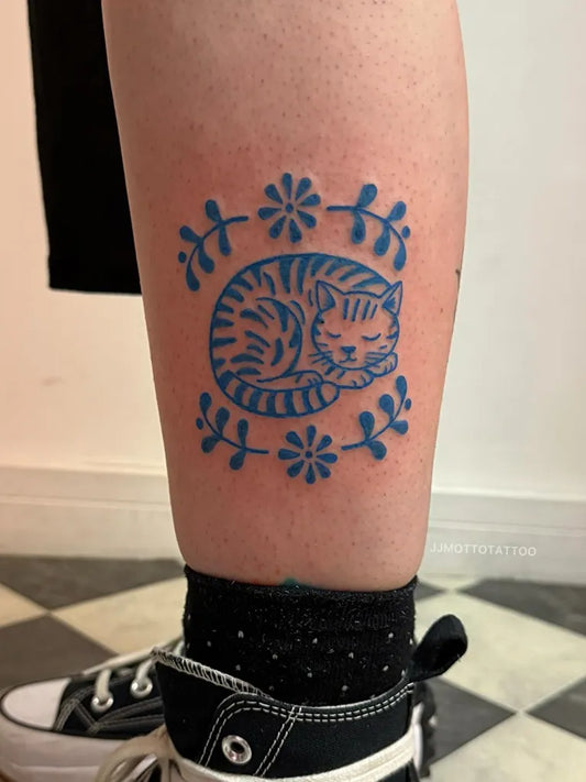 Small Blue Sleeping Tiger Cat with Flowers Tattoo on Women Leg by @jjmottotattoo