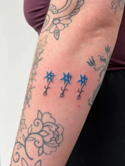 Small Blue Three Star Shaped Flowers Tattoo on Women Arm by @life.is.a.trash.can