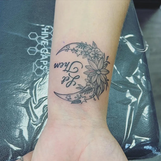 Small Botanical Cresent Moon Let Them on Women Wrist Tattoo by @porterstattoos
