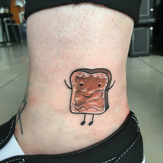 Small Cartoon Toast with Peanut Butter on Women Ankle Tattoo by @varsanyiangela_tattoo