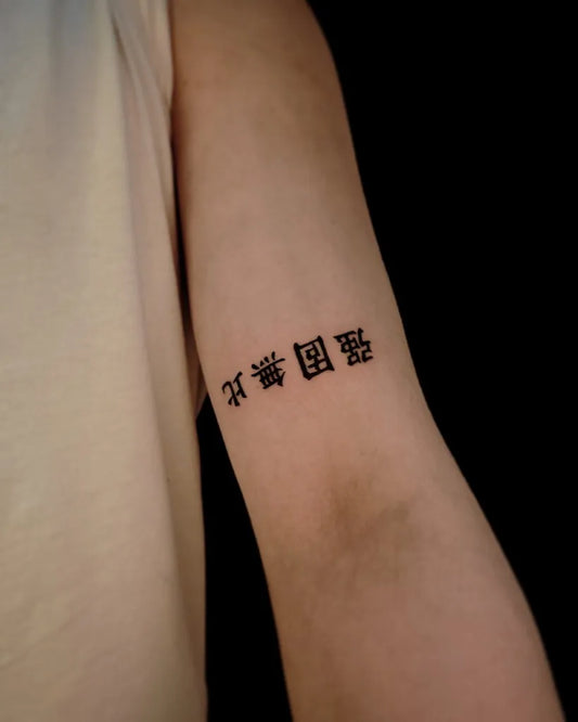 Small Chinese Immensely Strong Kanji Script Tattoo on Women Arm by @dozo.tattooist