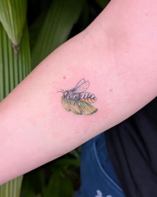 Small Color Bee with Leaf on Women Arm Tattoo by @twobees.tattoo