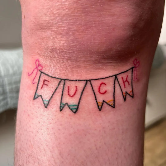 Small Colorful Banner Spelling Fuck Tattoo on Women Knee by @babbygail_doodles