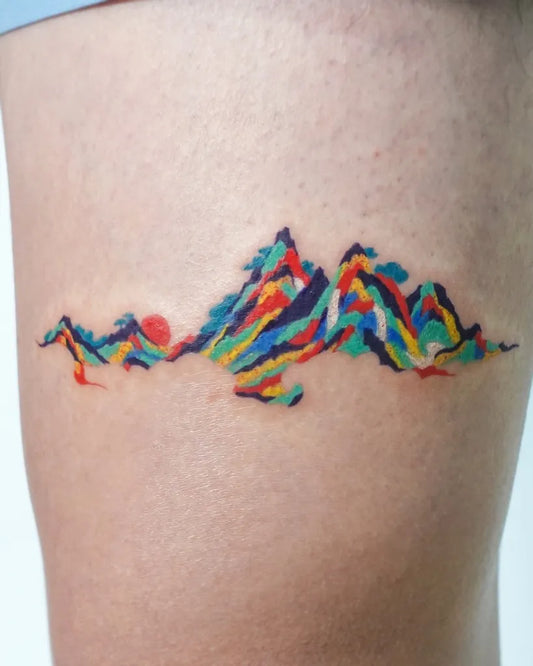 Small Colorful Mountain and Sun Tattoo on Women Thigh by @hansiitattoo