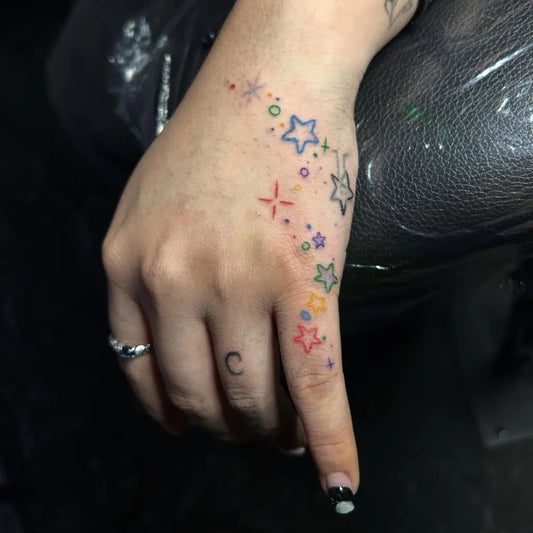 Small Colorful Rainbow Stars Tattoo on Women Wrist by @gracies.tattoo.therapy