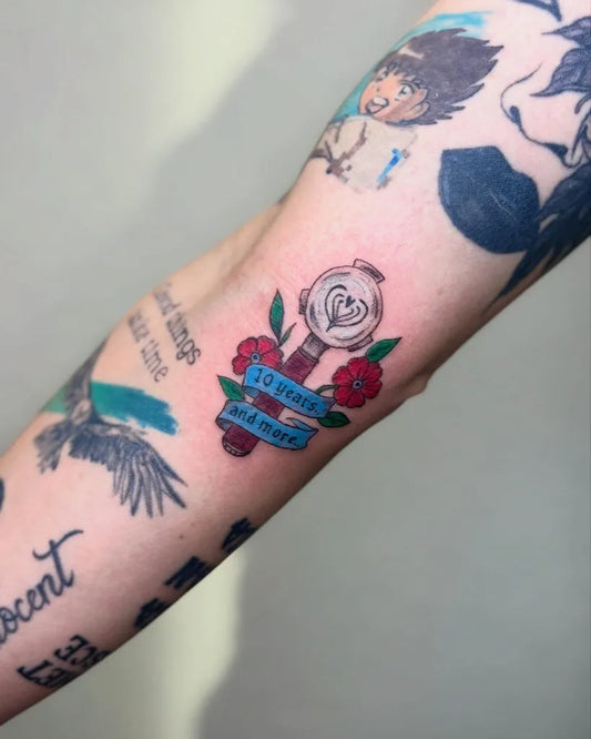 Small Colorful Spinning Heart Ribbon Tattoo on Women Arm by @giz.tattoo