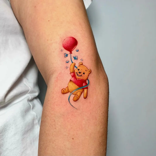 Small Colorful Winnie the Pooh with Red Balloon Tattoo on Women Arm by @ozgeiink