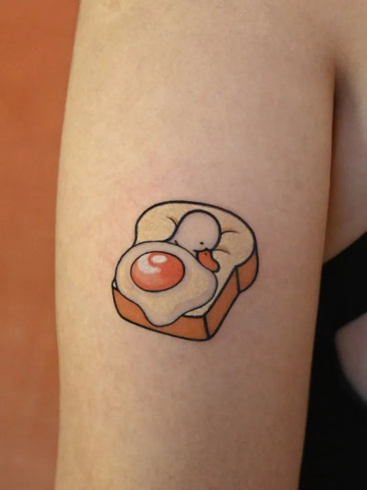 Small Cute Toast with Egg and Chick on Women Arm Tattoo by @luminousbanana_