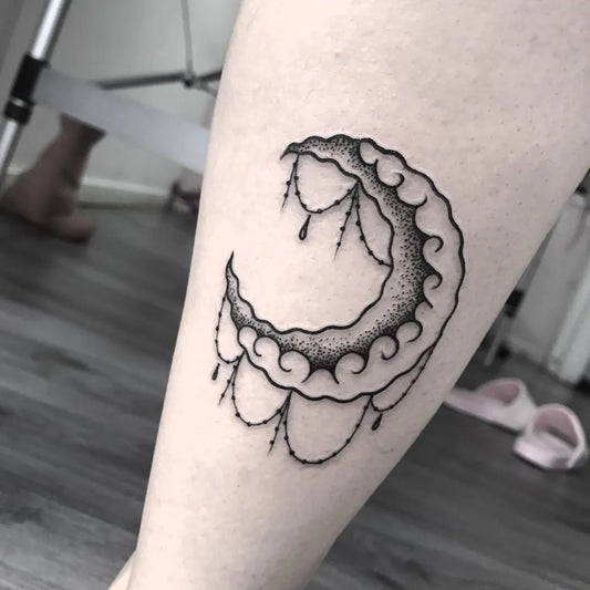 Small Dotwork Crescent Moon with Tassel Tattoo on Women Leg by @tinymamatattoo