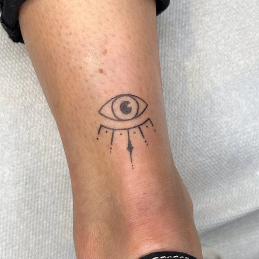 Small Dotwork Evil Eye with Rays on Women Ankle Tattoo by @handpokeme