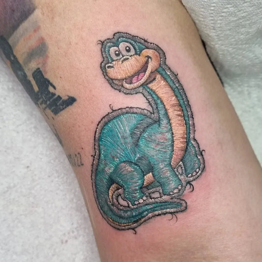 Small Embroidery Cartoon Dinosaur Tattoo on Men Arm by @sola.kaida