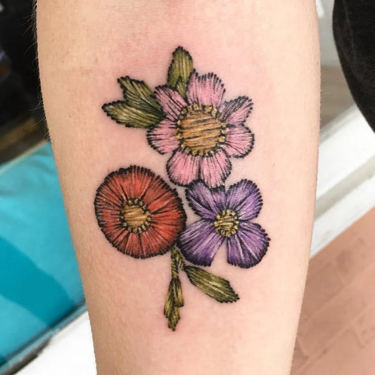Small Embroidery Colorful Flowers and Leaves Tattoo on Women Arm by @emilylouisetattoos