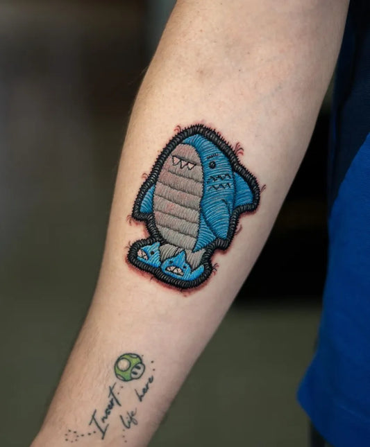 Small Embroidery Cute Blue Shark with Slippers Tattoo on Women Arm by @sublimetattoogt