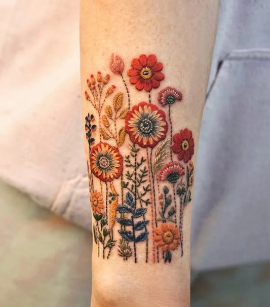Small Embroidery Red and Orange Flowers Tattoo on Women Arm by @ara__ink