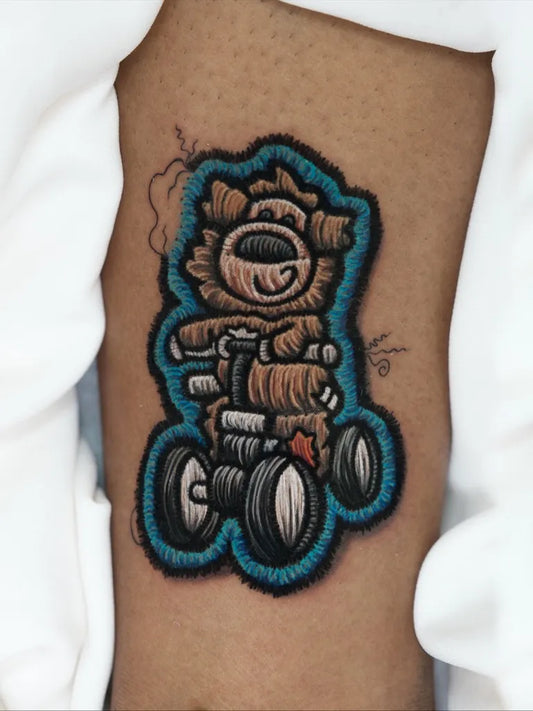 Small Embroidery Teddy Bear on Wheels Tattoo on Women Thigh by @noemi.bb.tattoo