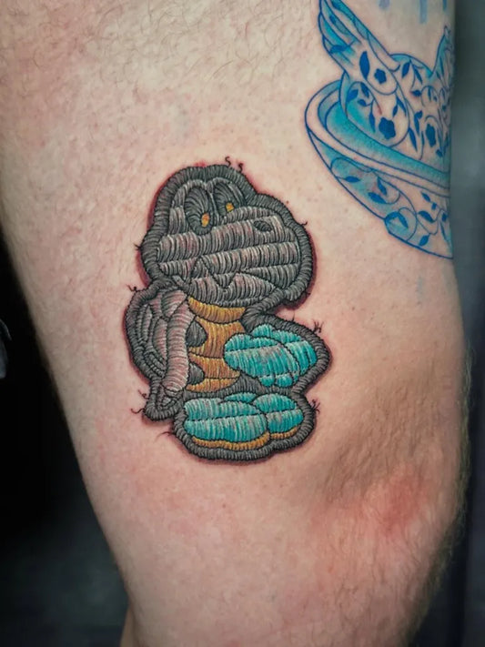 Small Embroidery Yoshi Tattoo on Men Leg by @phantastic_tattoos