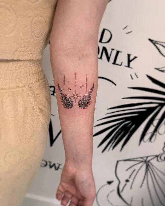 Small Fine Line Angel Wings Tattoo on Women Arm by @rayanetattoos