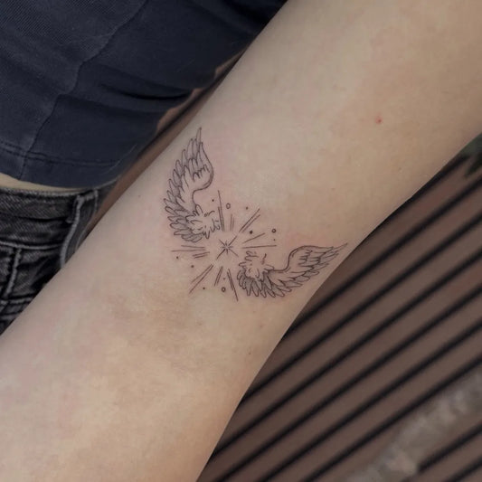 Small Fine Line Angel Wings With Stars Tattoo on Women Arm by @medusas_artistry