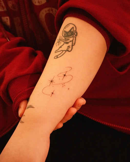 Small Fine Line Astronaut Cat and Stars Tattoo on Women Arm by @won_tattooer