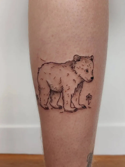 Small Fine Line Bear with Flower on Women Leg Tattoo by @transcendance.tattoo