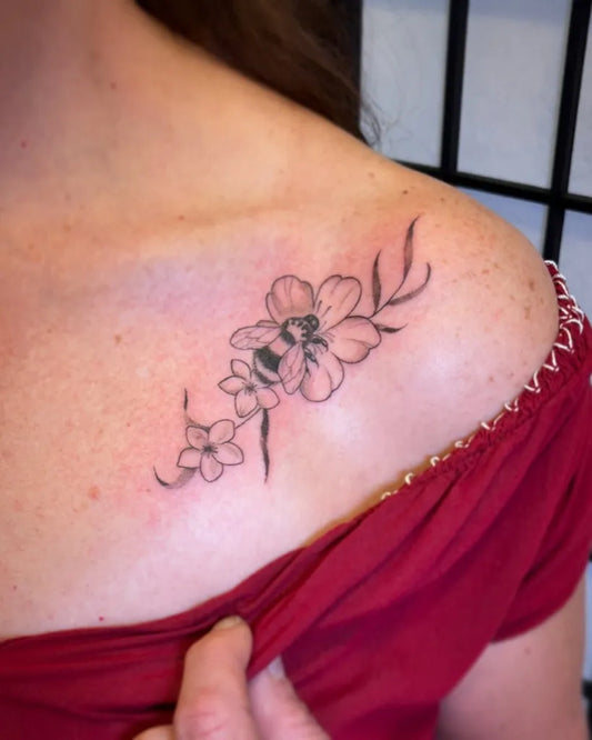 Small Fine Line Bee and Flowers Tattoo on Women Collarbone by @amp.tattoos