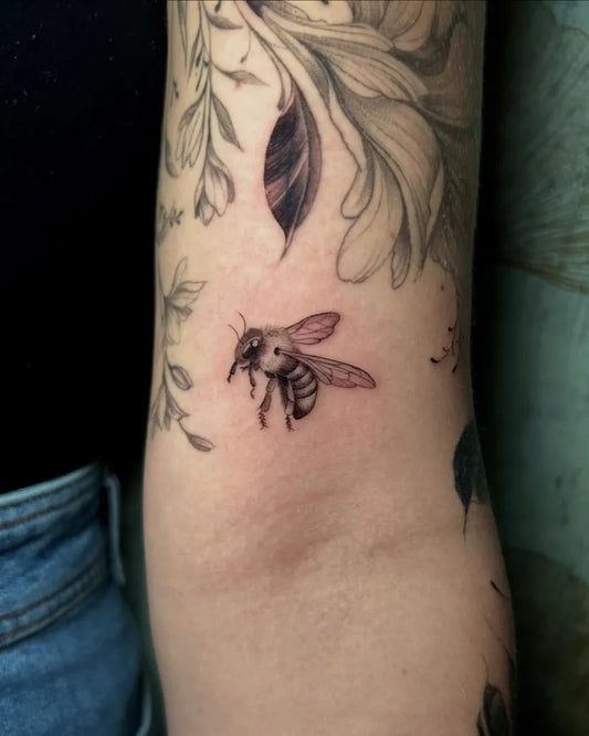 Small Fine Line Bee and Flowers on Women Arm Tattoo by @vixentatt__