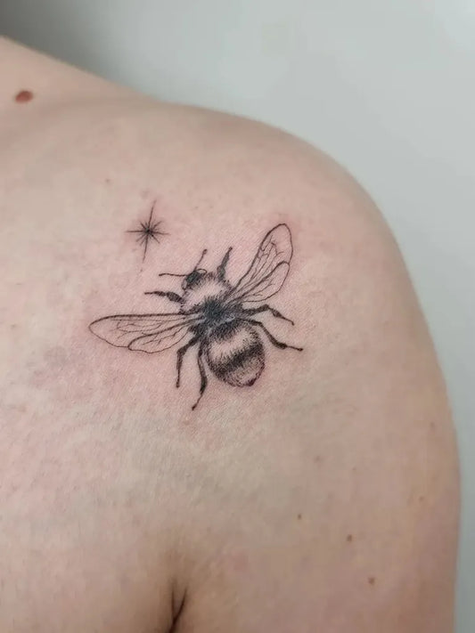 Small Fine Line Bee and Star on Women Shoulder Tattoo by @cnx_tattoo