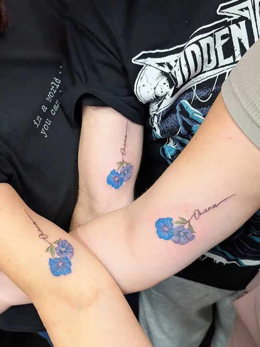Small Fine Line Blue Flower and Name Family Tattoo on Women Arm by @lunalanatattoo