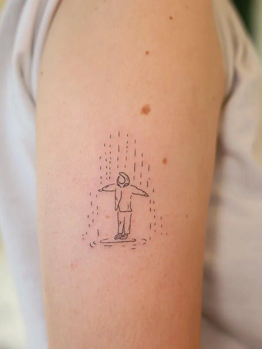 Small Fine Line Boy in Rain on Skateboard on Women Upper Arm Tattoo by @artrud_tattoo
