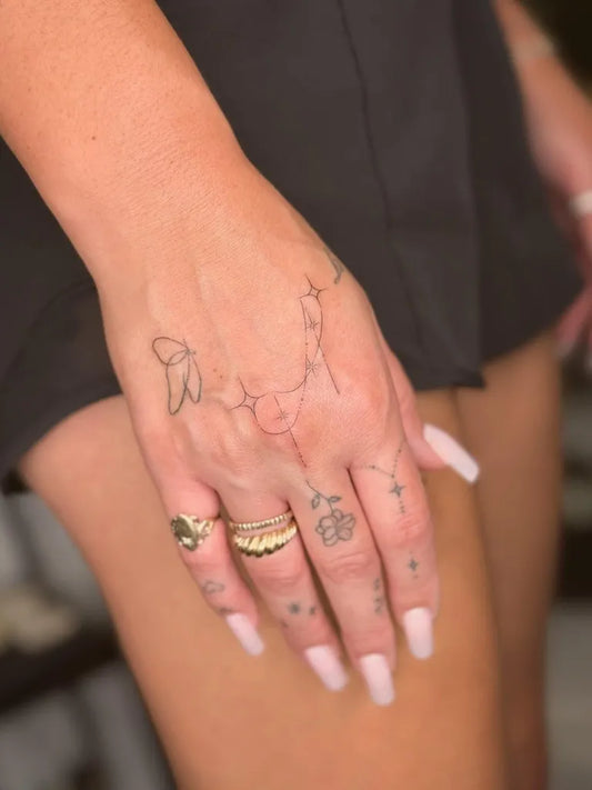 Small Fine Line Butterfly and Flower on Women Hand Tattoo by @tattoovasquez