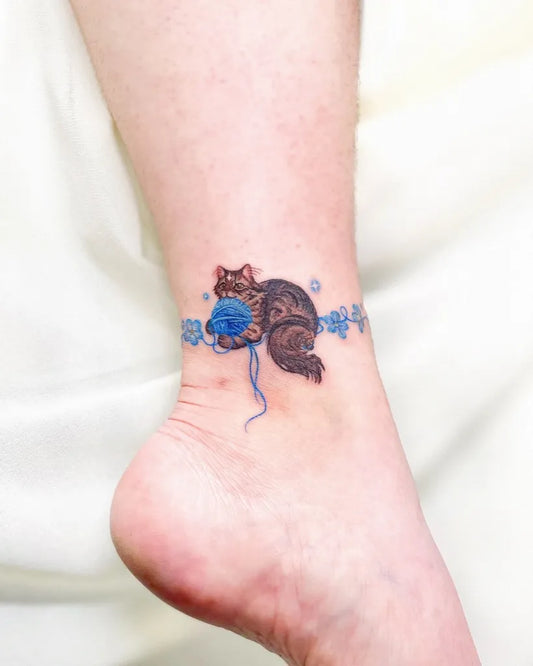 Small Fine Line Cat with Yarn Tattoo on Women Ankle by @peria_tattoo