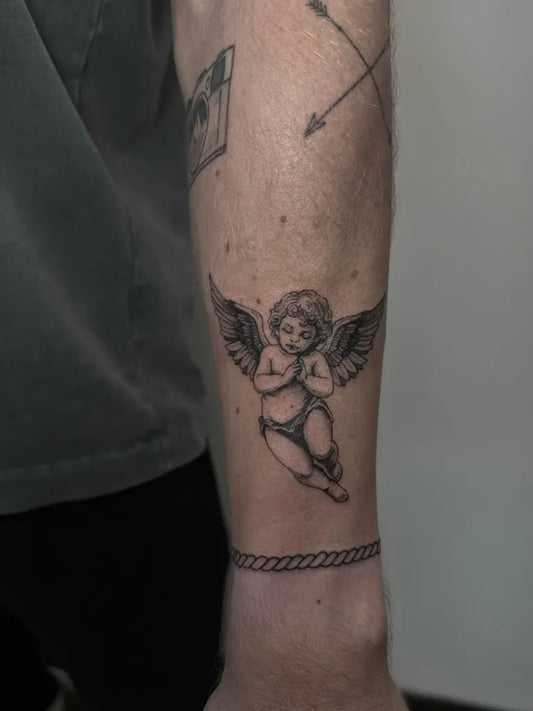 Small Fine Line Cherub Tattoo on Men Arm by @lucytattooz