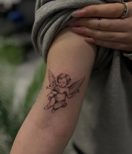 Small Fine Line Cherub Tattoo on Women Arm by @inkbymadelyn