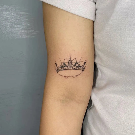 Small Fine Line Crown Tattoo on Women Arm by @pintadon_tattoo