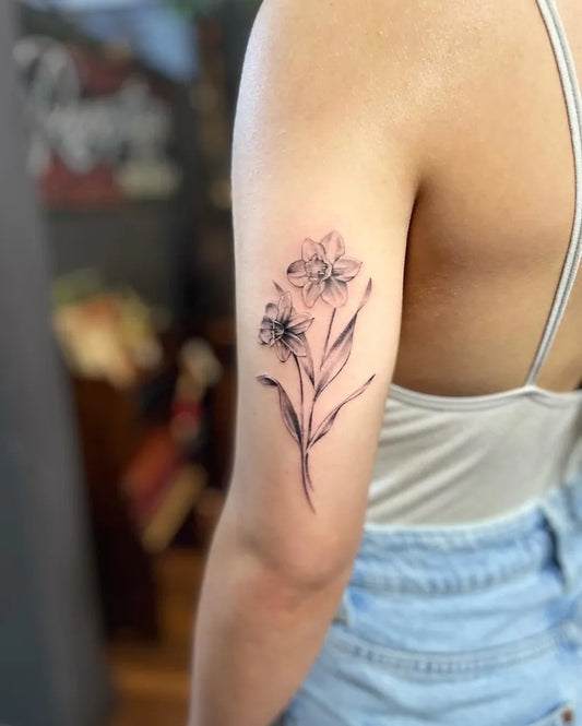 Small Fine Line Daffodil Flowers Tattoo on Women Upper Arm by @dpetattoolounge