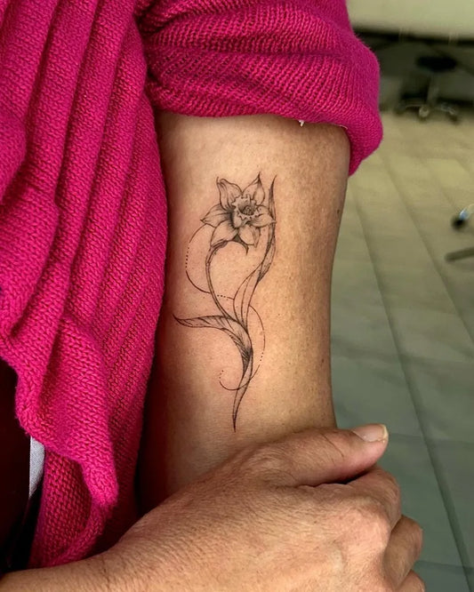 Small Fine Line Daffodil Tattoo on Women Arm by @cloudy.iink