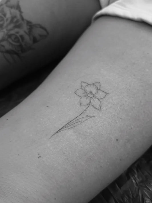 Small Fine Line Daffodil Tattoo on Women Thigh by @nanotattoos5
