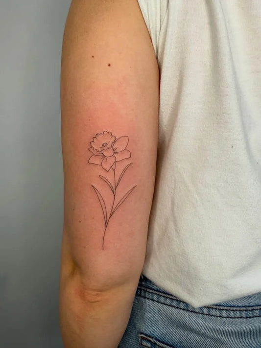 Small Fine Line Daffodil Tattoo on Women Upper Arm by @francielitattooart