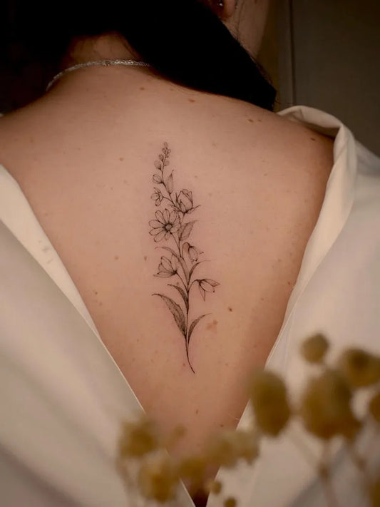 Small Fine Line Daisy Flowers Tattoo on Women Back by @zoe.fineline