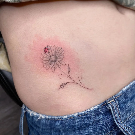 Small Fine Line Daisy and Ladybug Tattoo on Women Hip by @sophiespoonertattoo