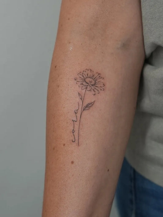 Small Fine Line Daisy with Name Women Arm by @soul_imagez_tattoo